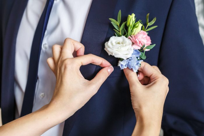 bride-corrects-groom-boutonniere-at-their-wedding-2025-03-08-04-24-07-utc Boutonnieres elegantes para novio y padrinos en una boda
